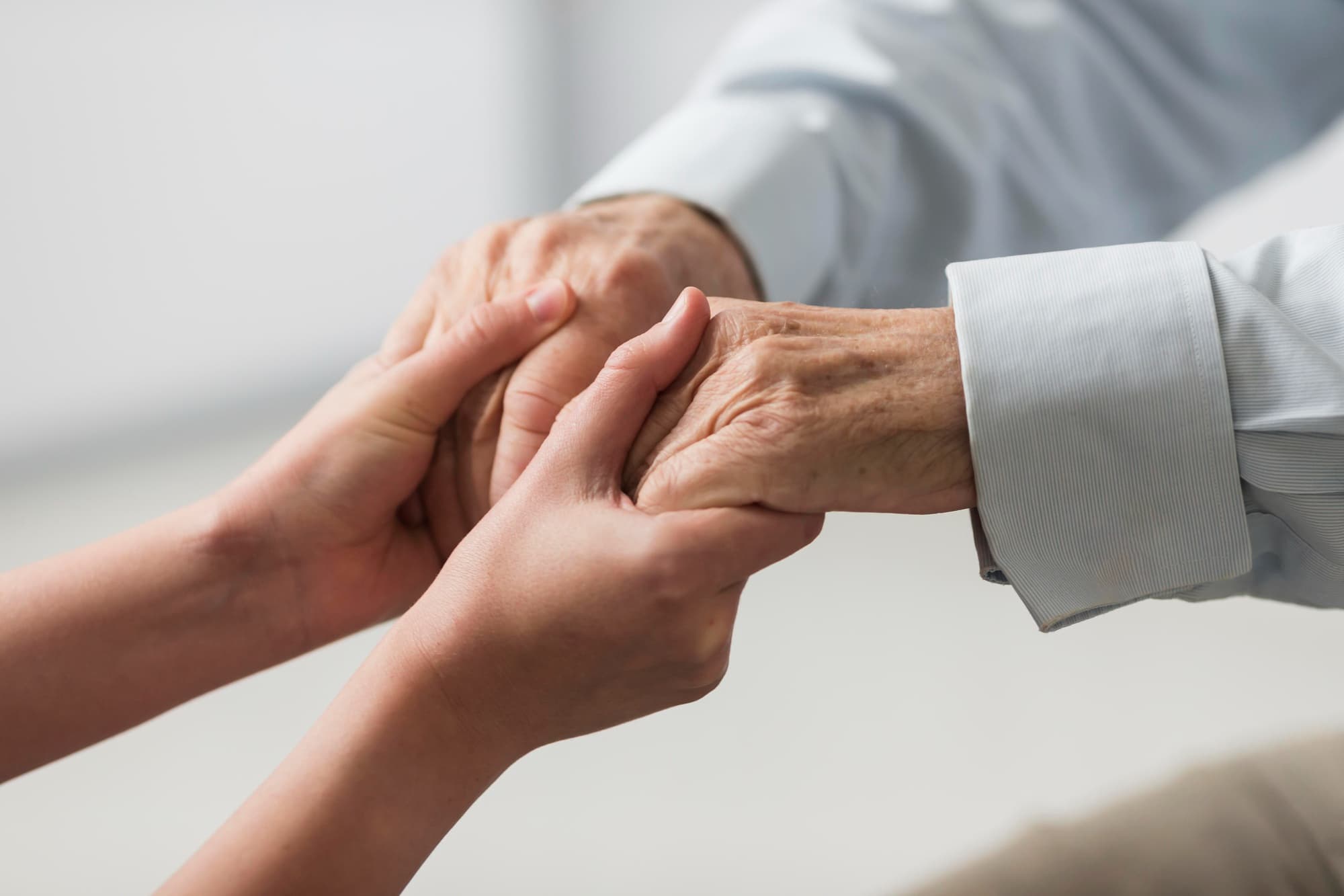 Caregiver holding elderly person's hands with warmth and compassion